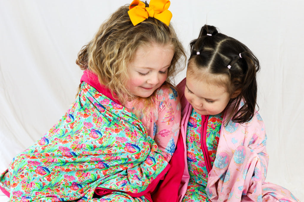 Two children in colorful pajamas sitting together on a white couch.