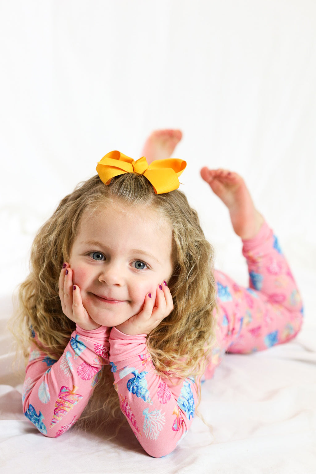 Child wearing a colorful outfit with a large yellow bow on a white background